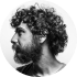 Black and white profile photo of a bearded man with curly hair.