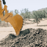 Excavator digging into the ground at a construction or mining site.