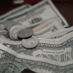 Close-up of scattered U.S. dollar bills and coins on a surface.