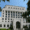 Government building with a grand white facade, tall pillars, and an arched entrance, surrounded by trees.