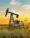 An oil pumpjack in a grassy field during sunset, symbolizing traditional energy sources.