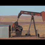 Rustic Lufkin oil pumpjack operating in a remote desert landscape, symbolizing traditional oil extraction.