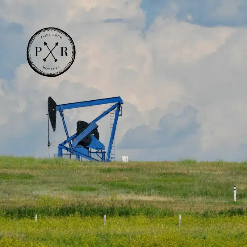 lue oil pumpjack operating in an open field with Paint Rock Royalty logo overlay.