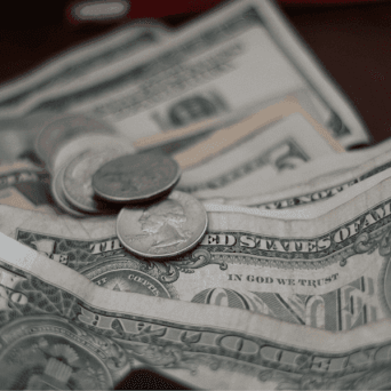 Close-up of scattered U.S. dollar bills and coins on a surface.